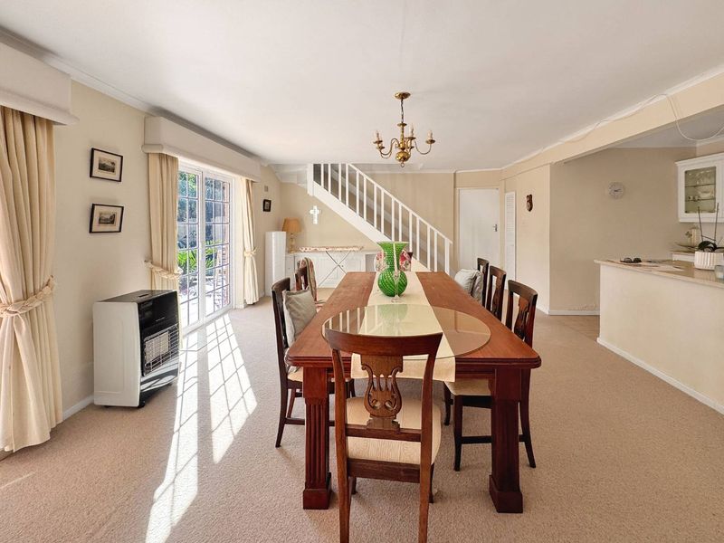 Spacious dining area featuring a staircase, neutral carpeting, and sliding glass doors providing access to the outdoor area.