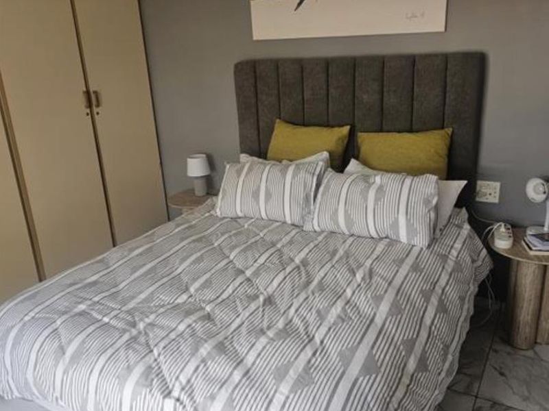 A well-maintained bedroom featuring neutral grey walls, tiled flooring, and a functional built-in wardrobe.