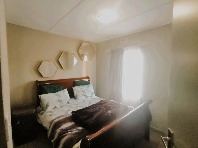 A standard bedroom featuring neutral wall tones and a window with natural light, providing a functional space for rest.