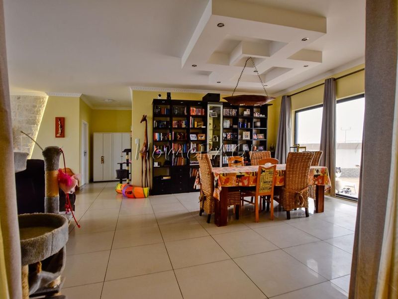 Spacious living and dining area featuring tiled floors, a decorative recessed ceiling, and large sliding glass doors providing natural light.