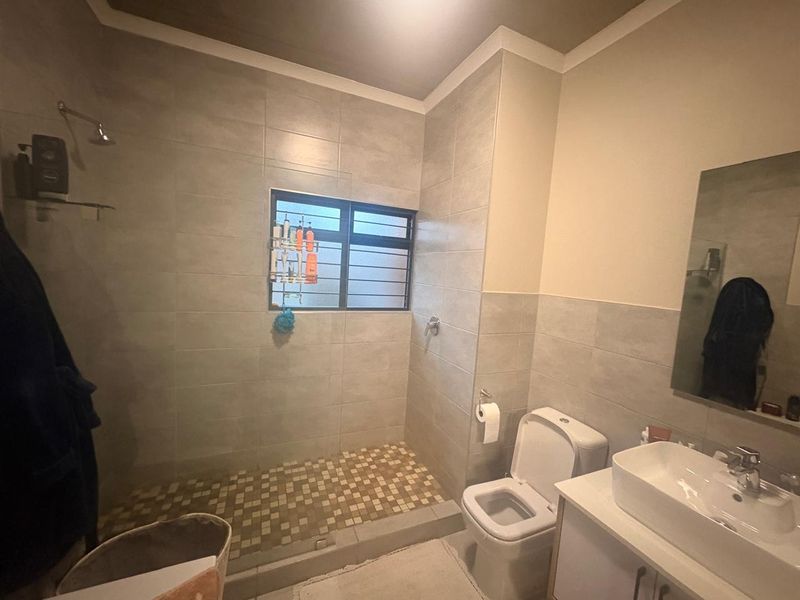 Modern bathroom featuring a walk-in shower with tiled flooring, a vanity with basin, and a wall-mounted mirror.