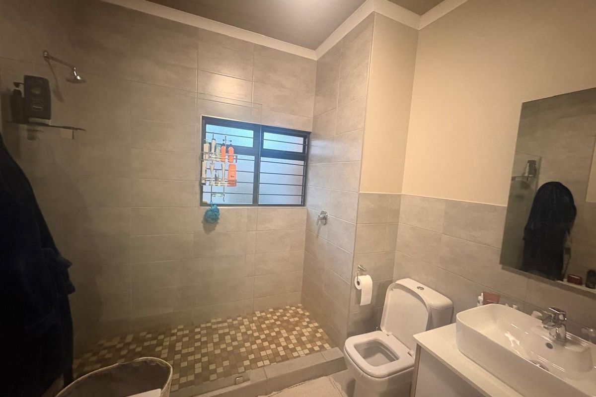 Modern bathroom featuring a walk-in shower with tiled flooring, a vanity with basin, and a wall-mounted mirror.