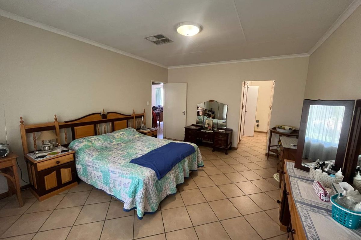 Spacious bedroom featuring tiled flooring and neutral wall finishes, offering a functional layout with direct access to an adjoining room.