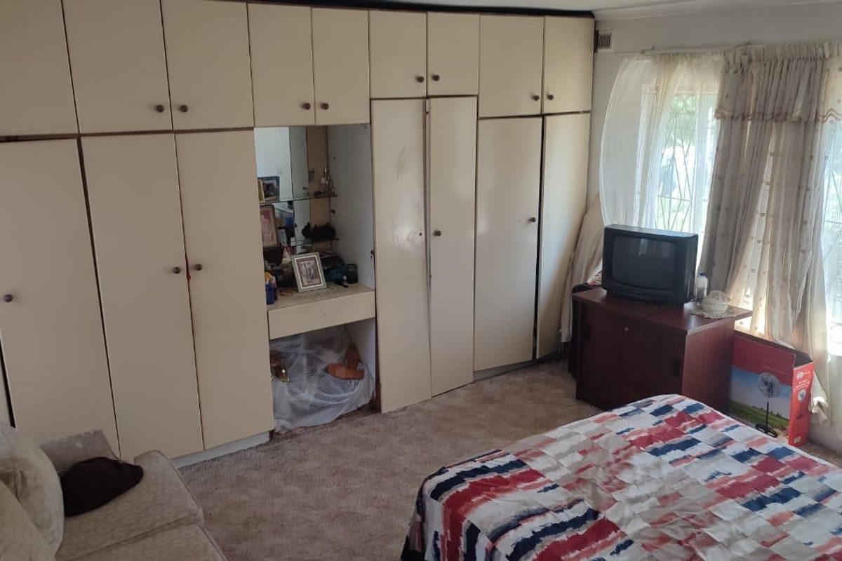 A bedroom featuring extensive floor-to-ceiling built-in cabinetry with a central vanity area and large windows with security bars.