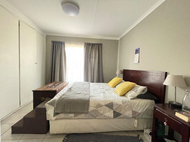 A functional bedroom featuring built-in cupboards, tiled flooring, and neutral wall finishes, providing a comfortable and practical living space.