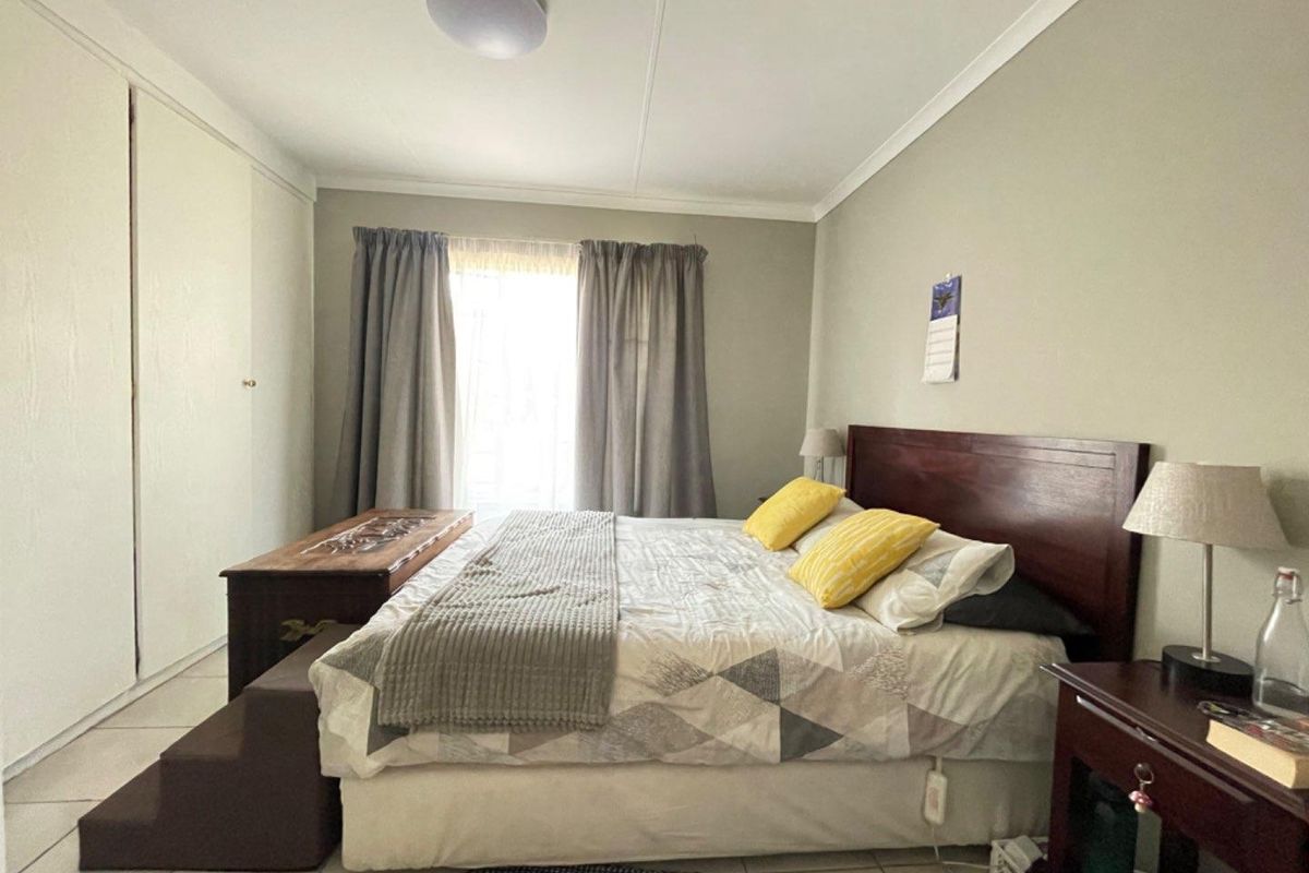 A functional bedroom featuring built-in cupboards, tiled flooring, and neutral wall finishes, providing a comfortable and practical living space.