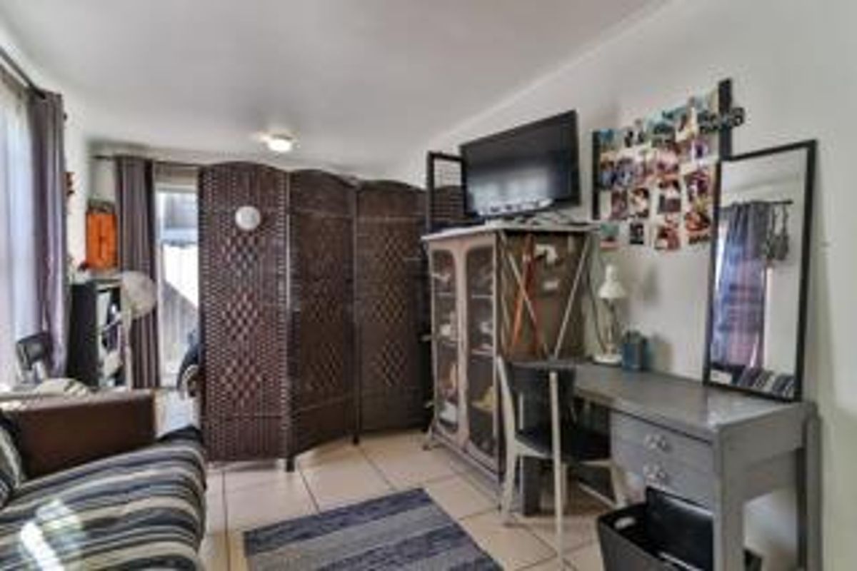 A functional living area featuring tiled flooring and access to an outdoor space through a sliding glass door.
