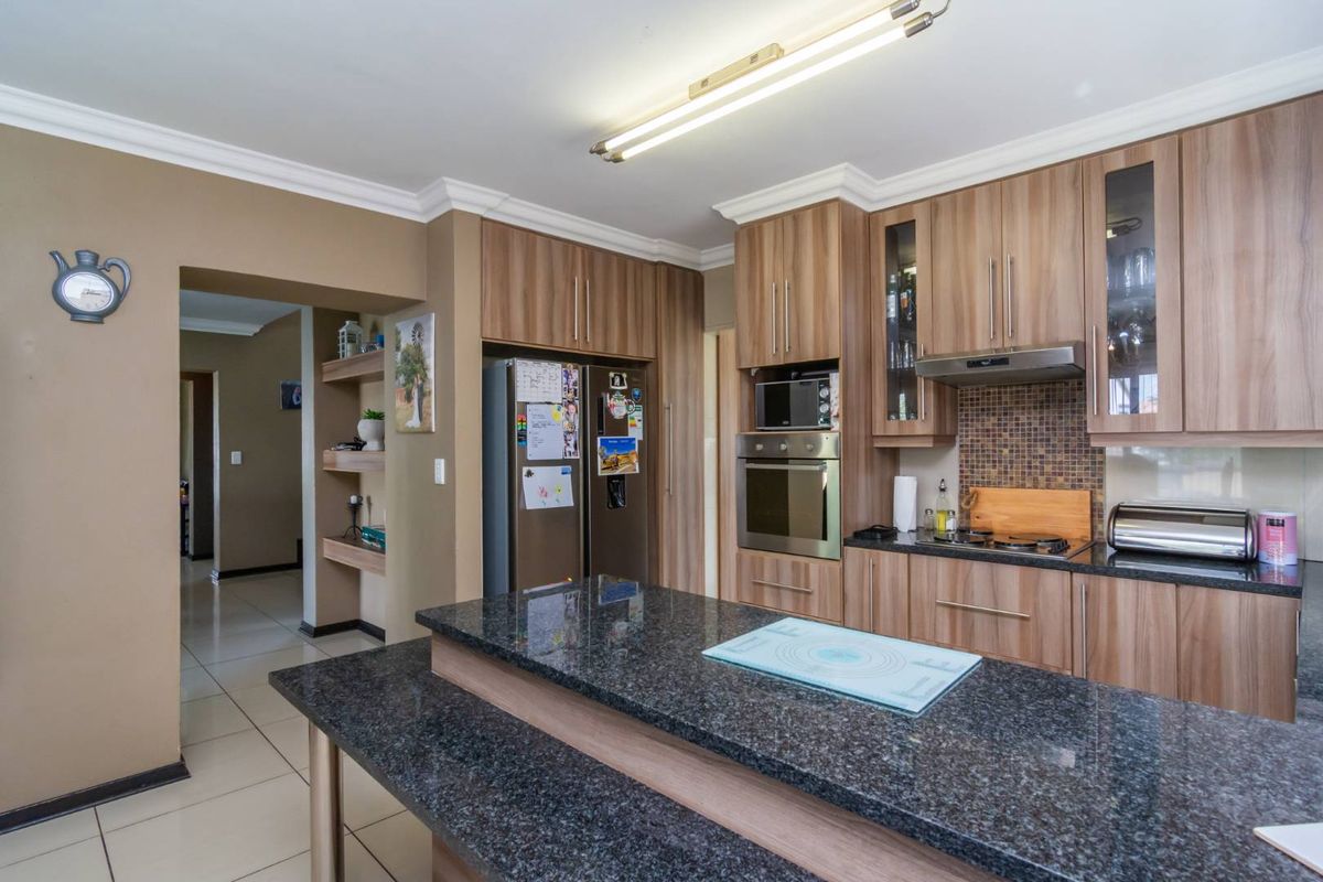 A functional kitchen featuring wood-grain cabinetry, granite countertops, a built-in oven, and a mosaic tile backsplash, with an integrated breakfast bar.