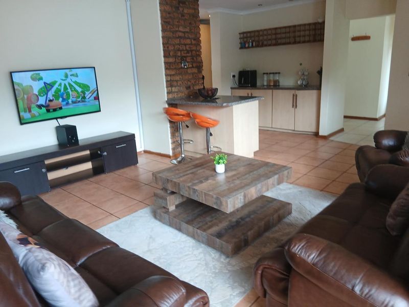 Open plan living and kitchen area featuring tiled floors, an exposed brick feature pillar, and a granite breakfast bar.