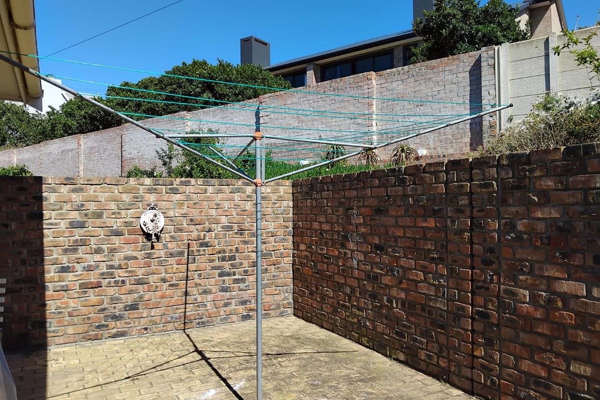 A private outdoor utility area featuring brick boundary walls and paved flooring, suitable for laundry drying or general outdoor storage.