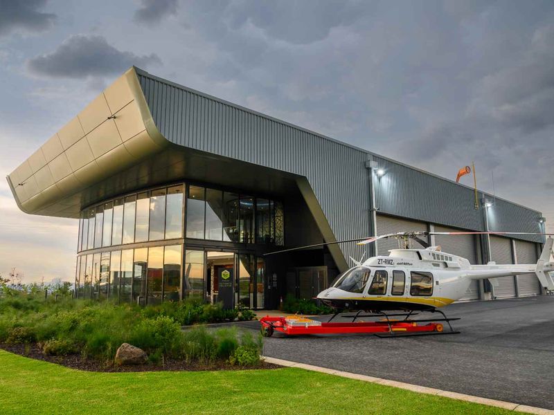 Modern commercial hangar facility featuring sleek metal cladding, extensive glass facade, and paved apron area, presenting a professional and well-maintained exterior aesthetic.