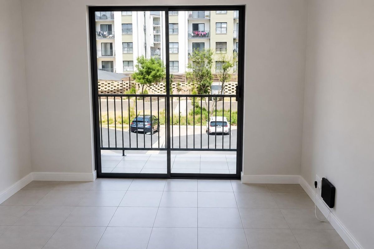 A bright, empty living area featuring neutral tiled flooring and a large sliding glass door leading to a balcony.