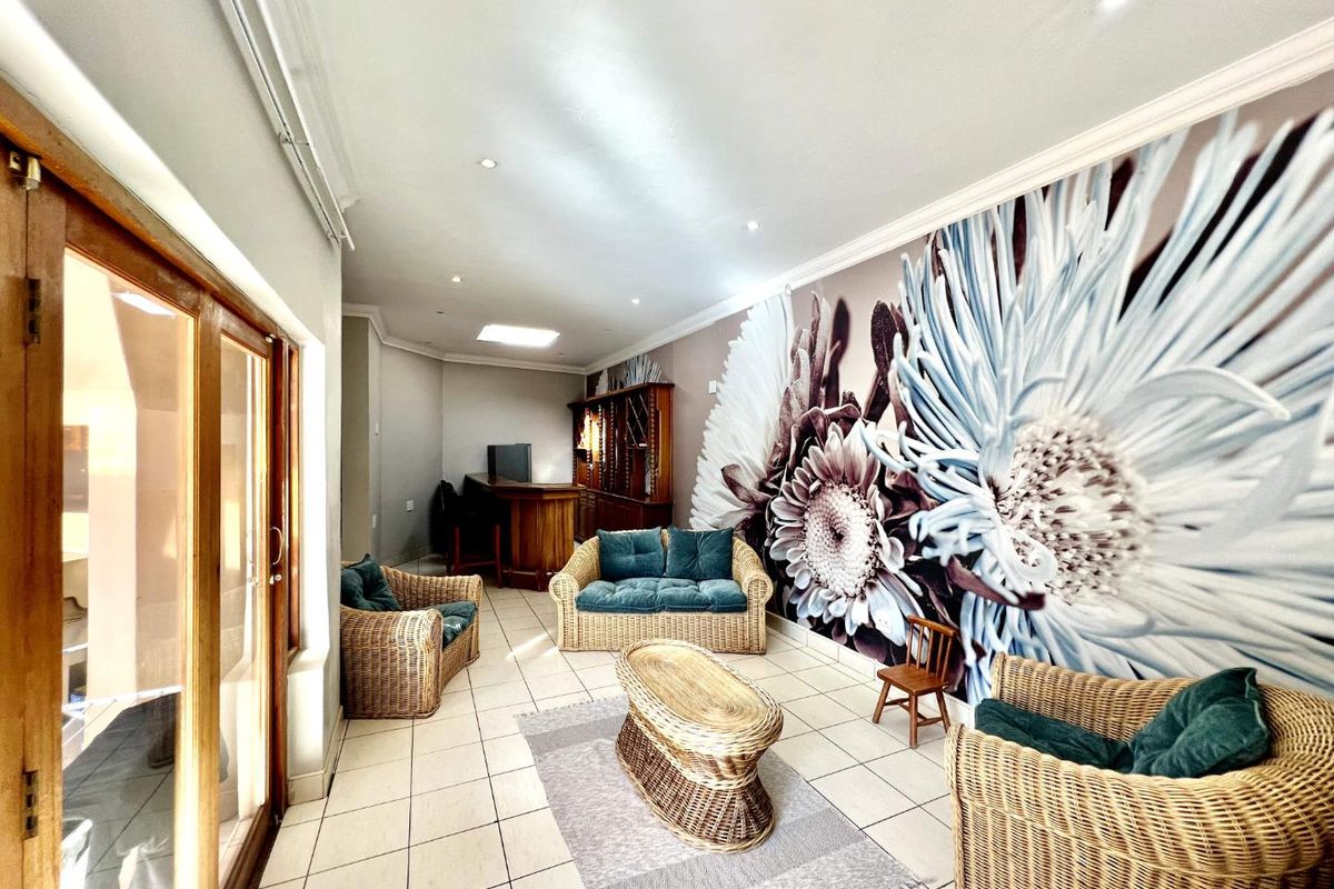 Spacious living area featuring tiled flooring, a built-in bar, a skylight, and large sliding glass doors providing access to the exterior.