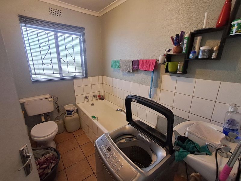 A functional bathroom featuring a bathtub, toilet, and washbasin with tiled splashbacks and tiled flooring.