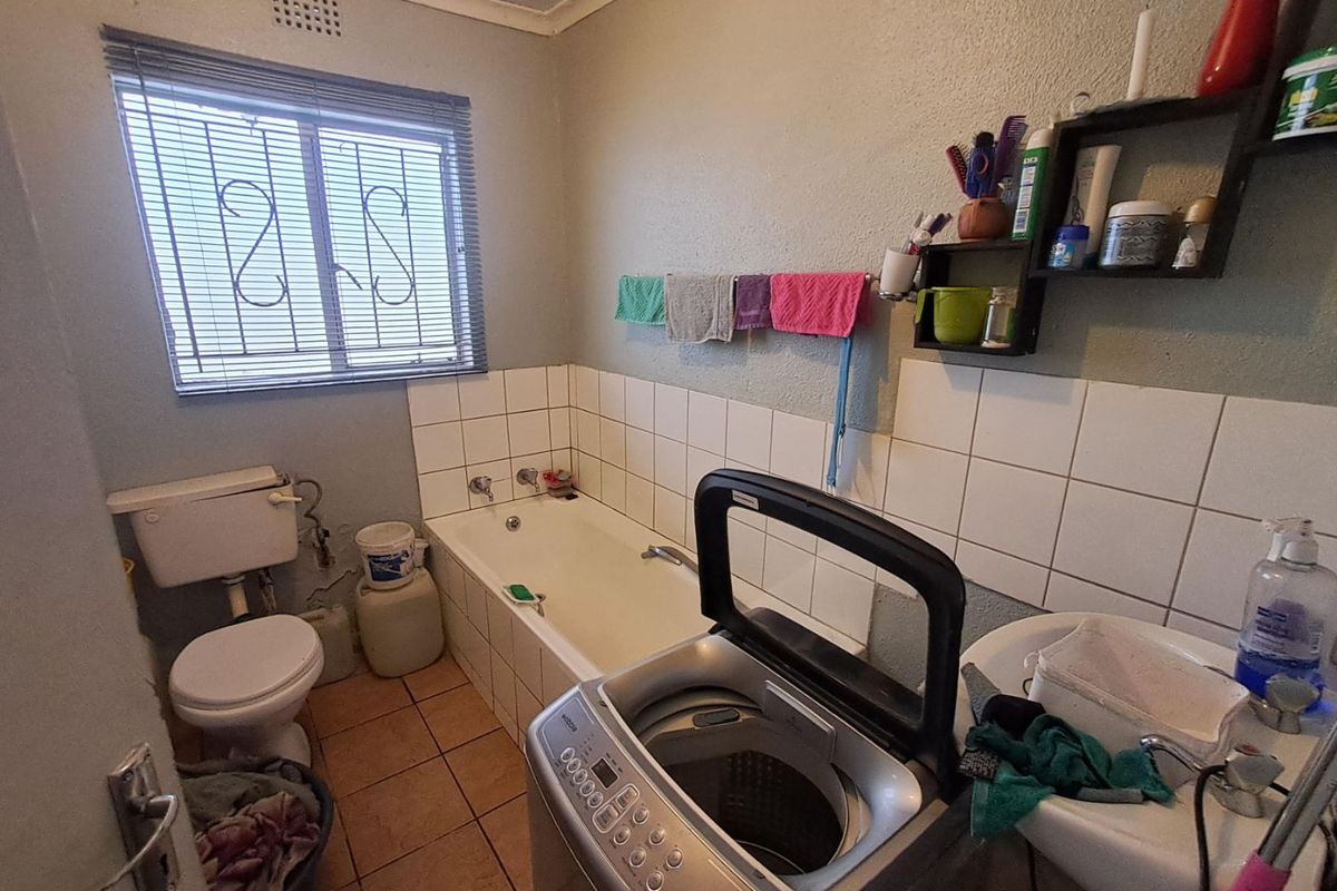 A functional bathroom featuring a bathtub, toilet, and washbasin with tiled splashbacks and tiled flooring.