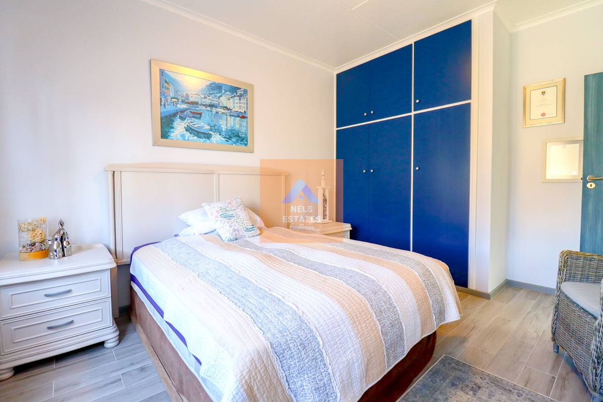 A bedroom featuring built-in blue cabinetry and light-toned wood-look flooring.