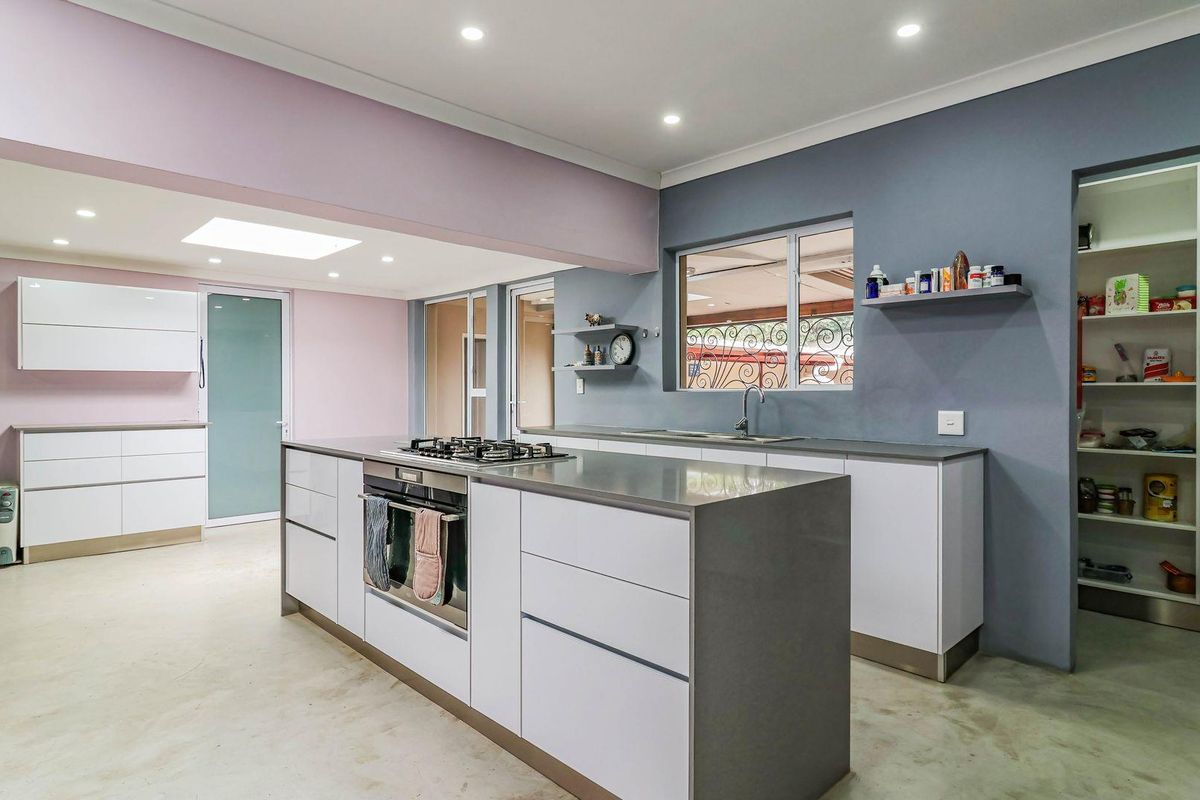 Modern open-plan kitchen featuring a central island with built-in gas hob and oven, sleek cabinetry, and an integrated walk-in pantry.