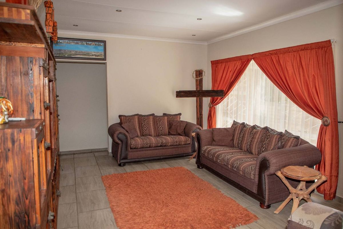 A comfortable living room featuring tiled flooring, recessed ceiling lighting, and large windows dressed with curtains, providing a functional and inviting space.