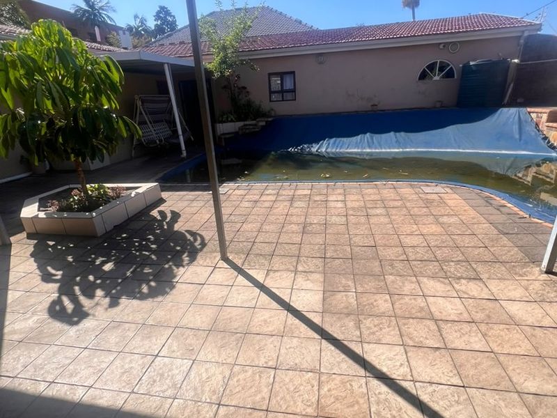 Outdoor entertainment area featuring a covered patio, tiled flooring, and a swimming pool with a cover.