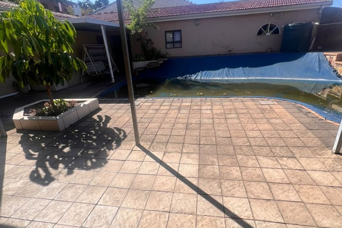 Outdoor entertainment area featuring a covered patio, tiled flooring, and a swimming pool with a cover.