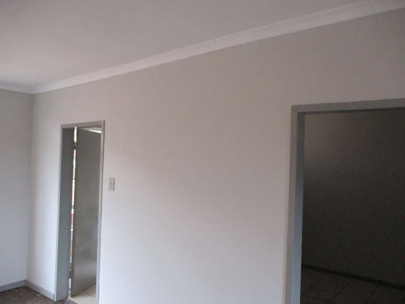 A neutral, empty hallway space featuring clean walls, cove cornicing, and two doorways leading into adjacent rooms.