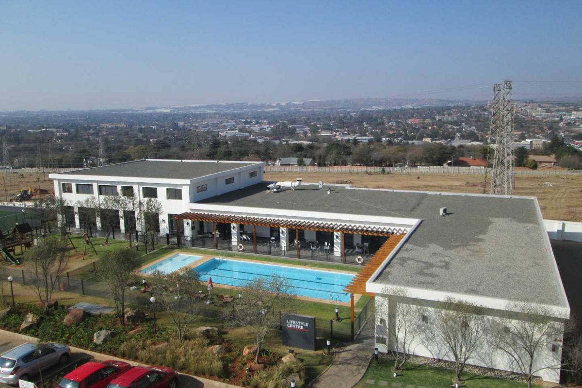 Aerial view of the apartment complex lifestyle centre featuring a swimming pool, covered patio area, and landscaped grounds.