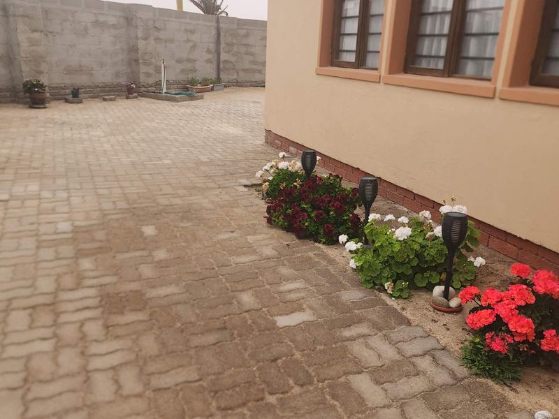 A paved rear courtyard area featuring a concrete block boundary wall and exterior access to the main dwelling.