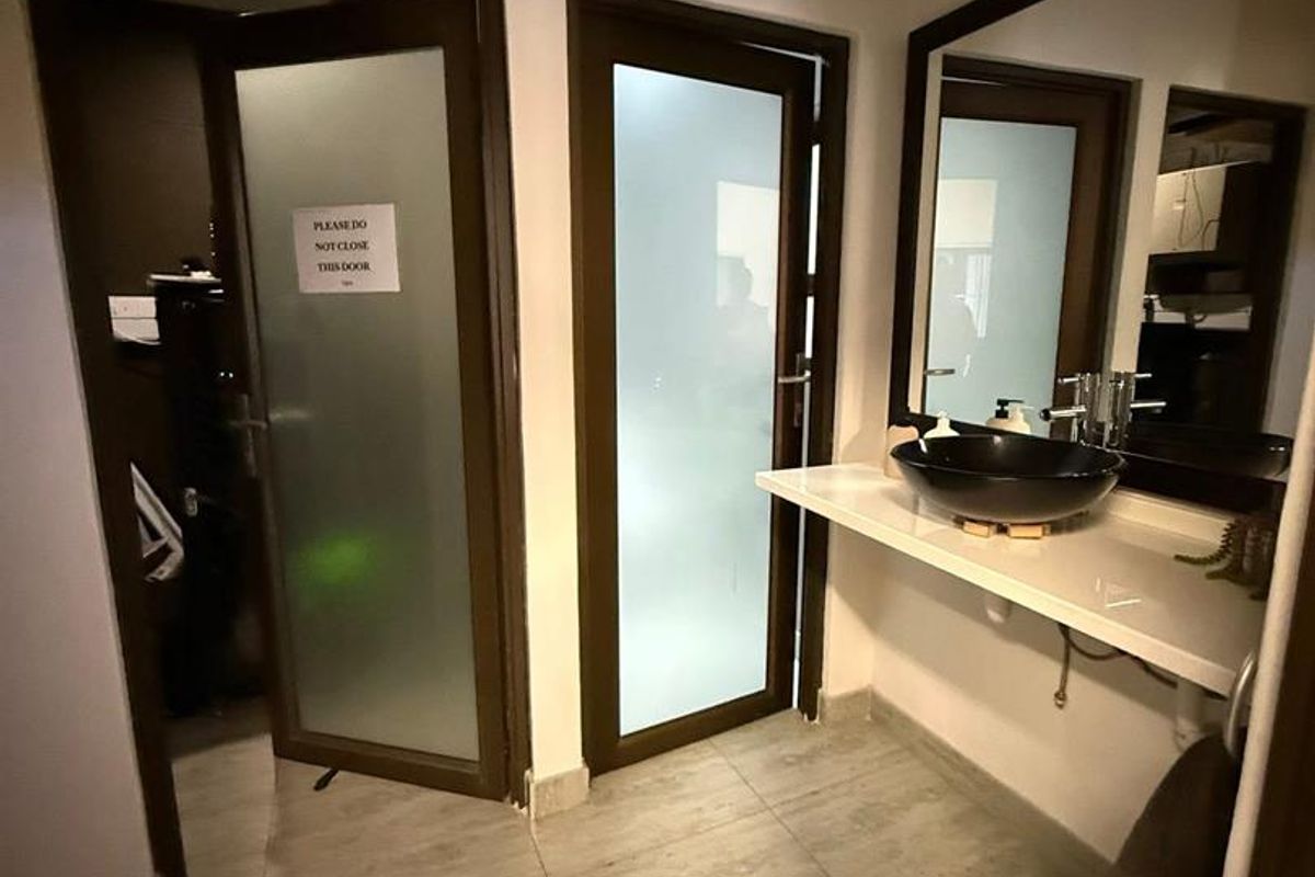 A functional office bathroom featuring a modern vessel sink, vanity mirror, and frosted glass doors providing privacy.