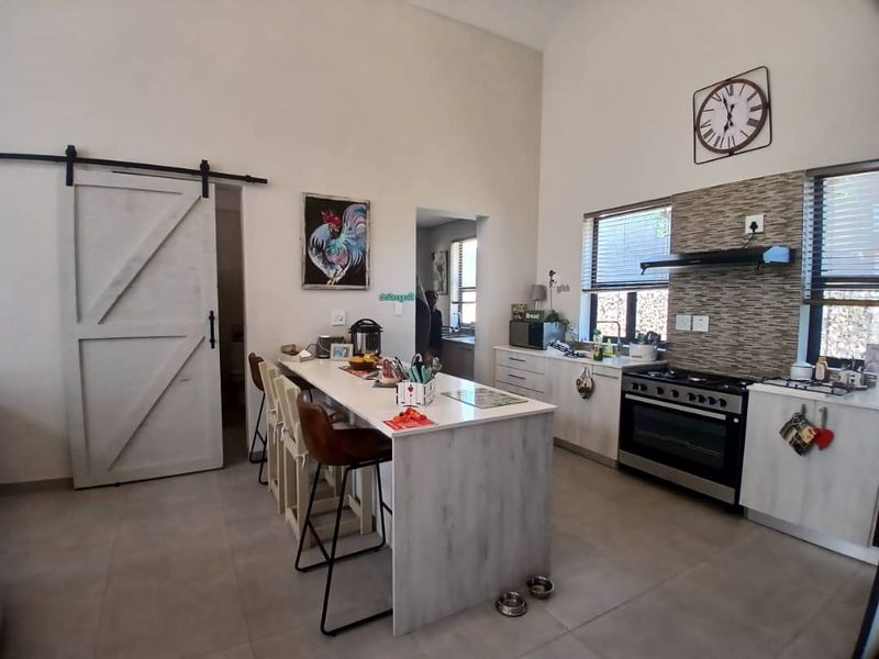 Modern kitchen featuring a central island, barn-style sliding door, gas stove with extractor fan, and contemporary tiled backsplash.