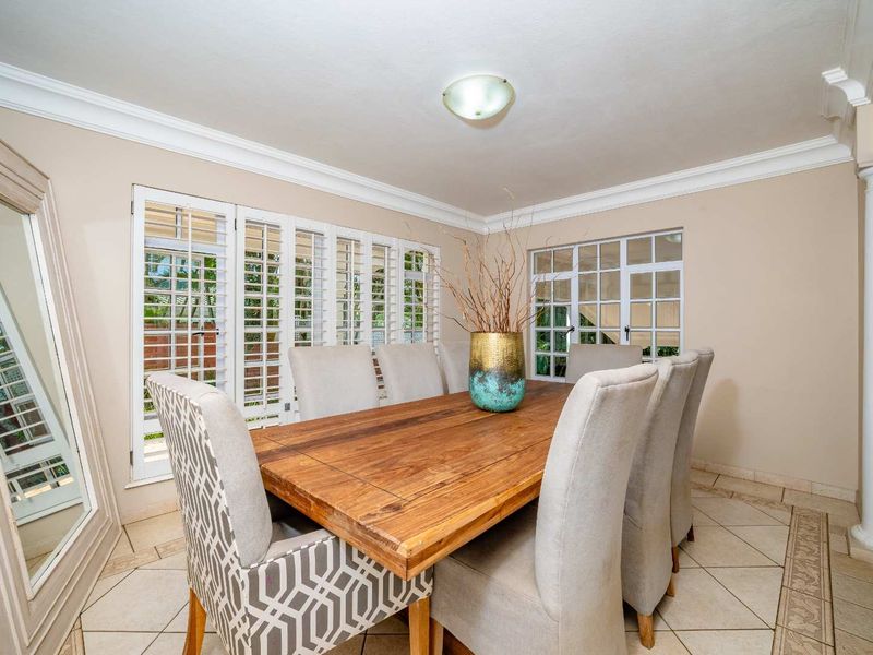 A well-lit dining room featuring tiled flooring, crown molding, and plantation shutters, providing a bright and inviting space for meals.