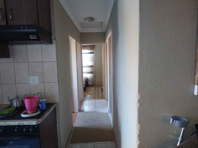 A view from the kitchen area looking into a hallway, featuring tiled flooring and a built-in oven with an extractor fan.