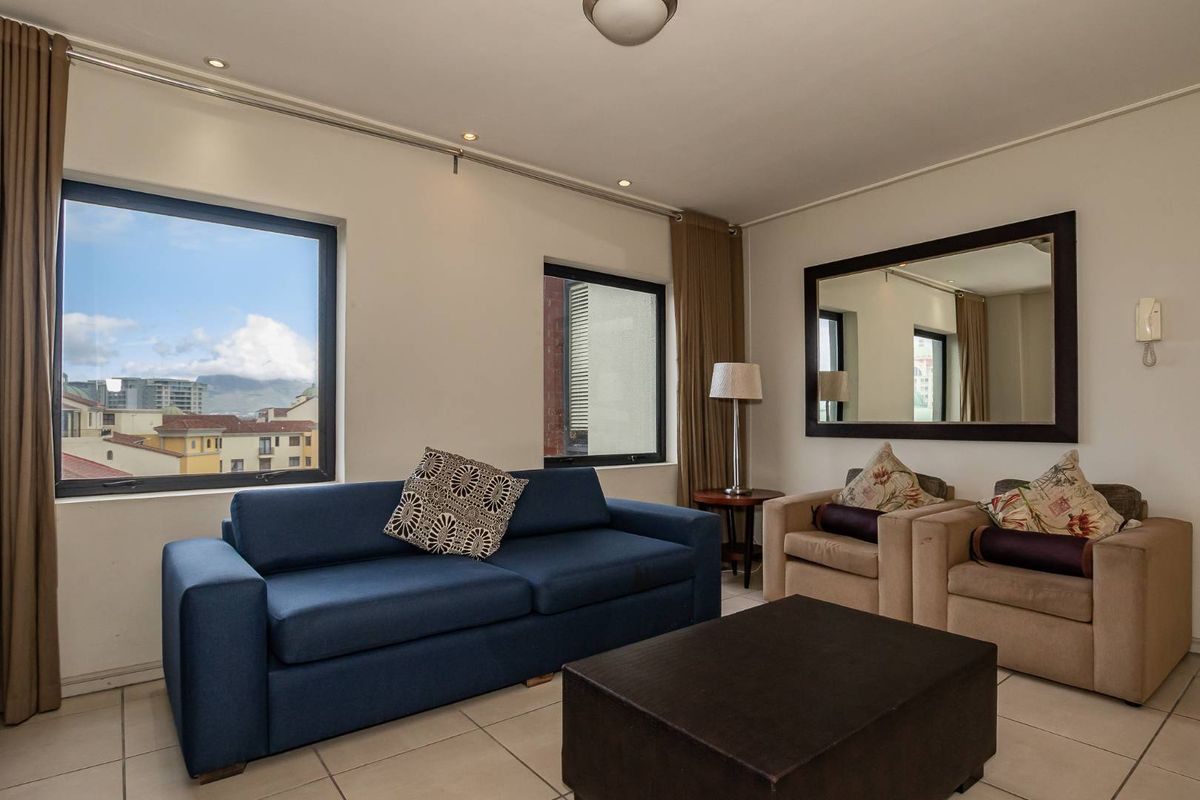 A bright living room featuring large windows with views, tiled flooring, and neutral wall finishes, providing a comfortable and functional space.