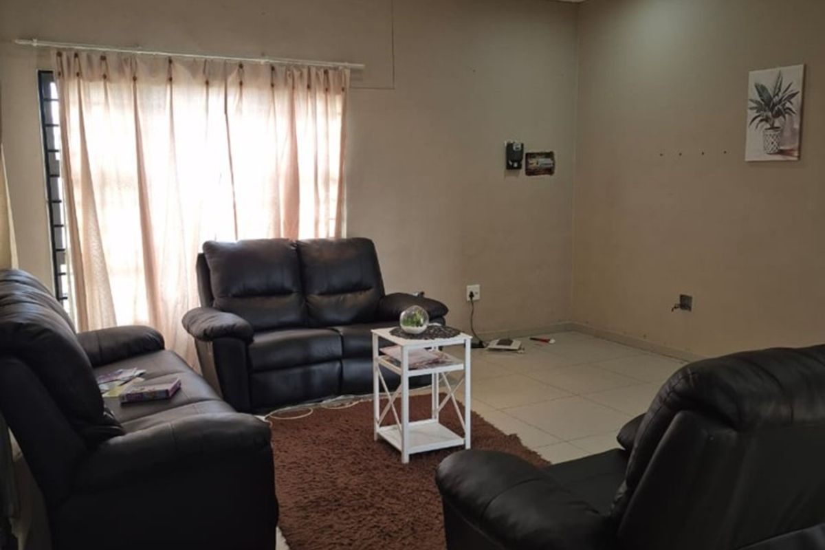 A spacious living room featuring neutral tiled flooring and recessed downlighting, providing a functional and well-lit area for relaxation.
