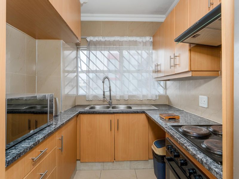 A functional kitchen featuring laminate cabinetry, granite countertops, a double basin sink, and built-in electric stove with an extractor fan.