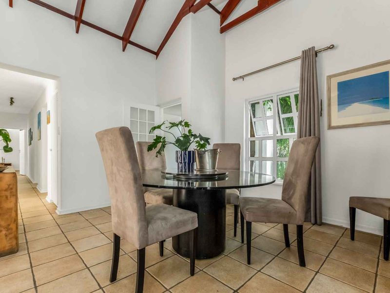 A bright dining area featuring a high vaulted ceiling with exposed timber trusses and classic tiled flooring, creating an airy and inviting atmosphere.