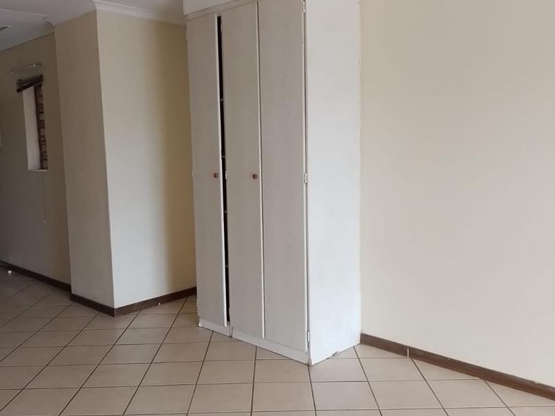 An empty hallway featuring neutral wall paint, ceramic floor tiles, and a built-in storage cupboard.