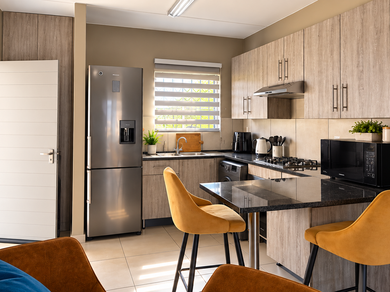 Modern kitchen featuring wood-look cabinetry, granite countertops, a built-in gas hob with extractor, and tiled flooring, offering a functional and contemporary cooking space.