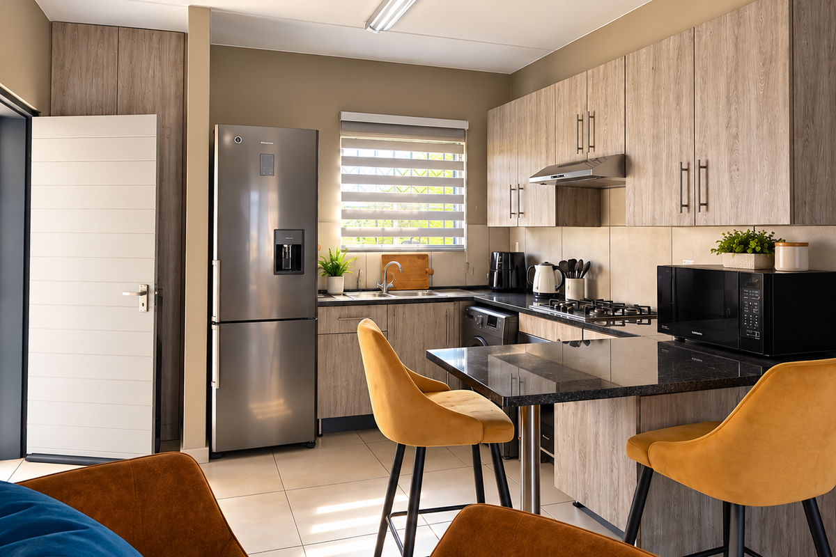 Modern kitchen featuring wood-look cabinetry, granite countertops, a built-in gas hob with extractor, and tiled flooring, offering a functional and contemporary cooking space.