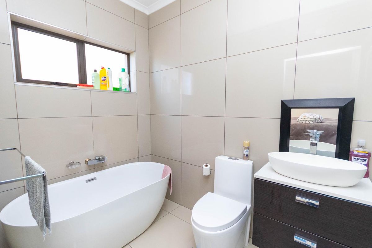 Modern bathroom featuring a freestanding bathtub, a contemporary vanity with a vessel sink, and floor-to-ceiling neutral wall tiling.