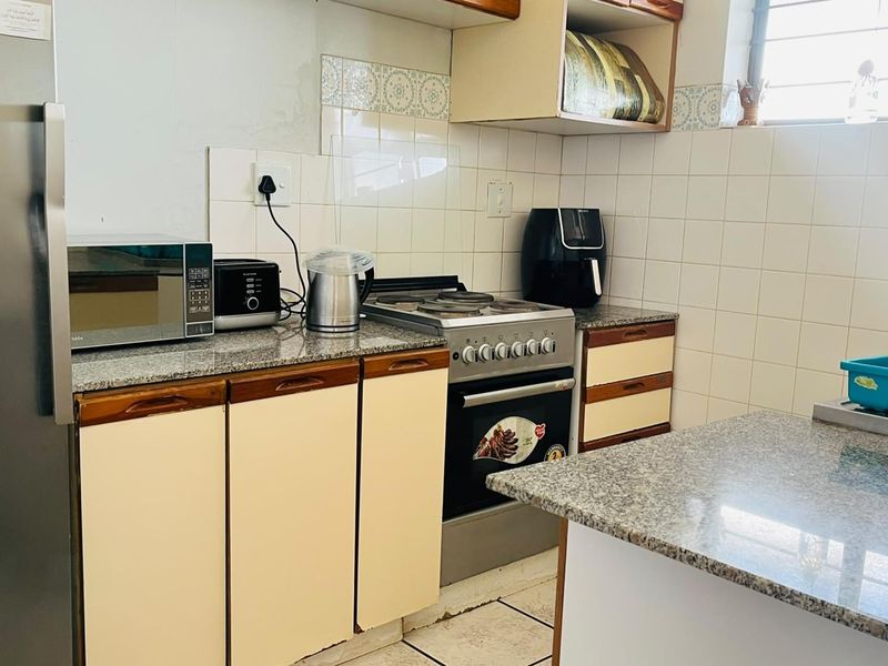 A functional kitchen featuring granite countertops, tiled backsplash, and built-in cabinetry, offering a practical layout for daily meal preparation.