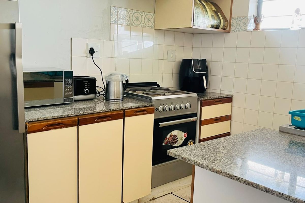 A functional kitchen featuring granite countertops, tiled backsplash, and built-in cabinetry, offering a practical layout for daily meal preparation.