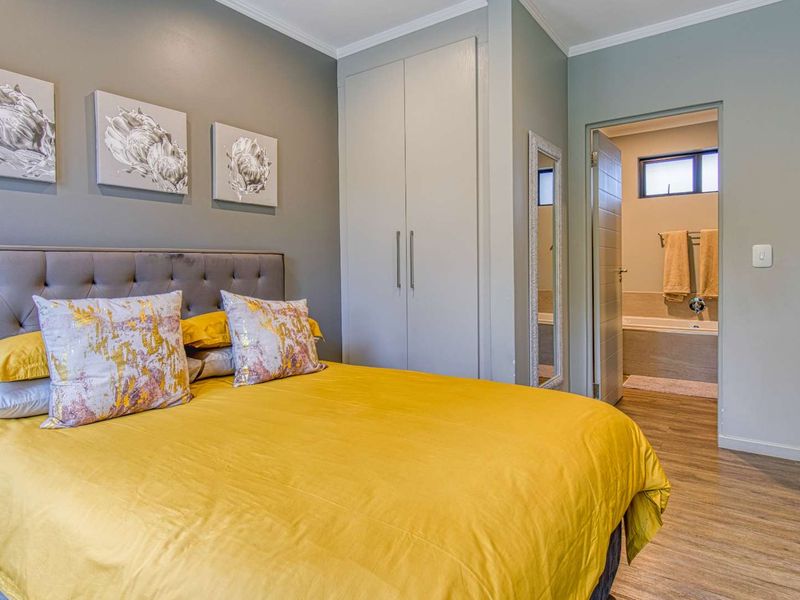 A well-maintained bedroom featuring laminate flooring, built-in cupboards, and direct access to an en-suite bathroom.