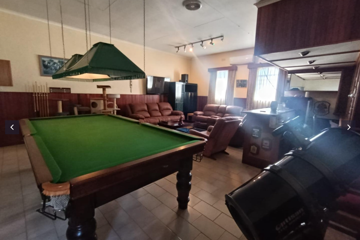 Spacious living area featuring wood paneling, tiled flooring, a built-in bar, and dedicated space for a pool table.
