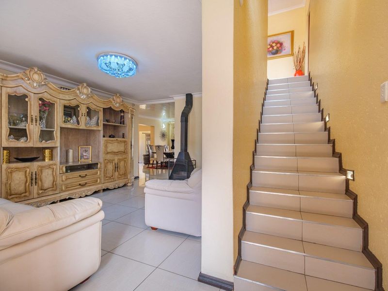 Open plan living area featuring a tiled staircase with integrated lighting and a central freestanding fireplace, leading through to the dining space.