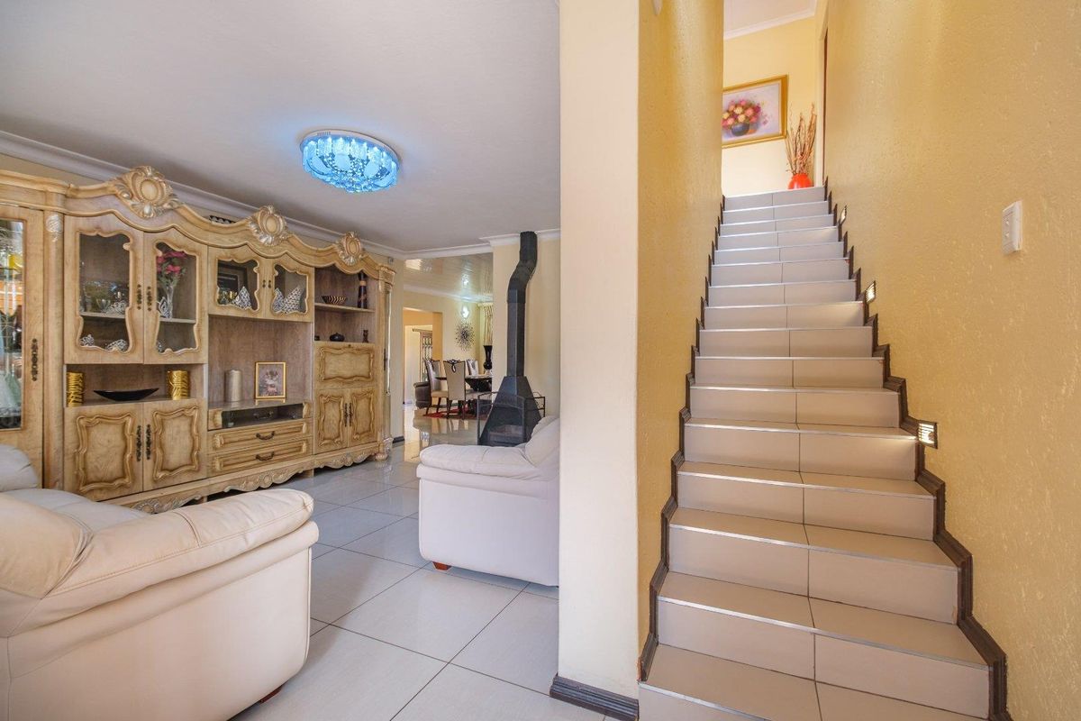 Open plan living area featuring a tiled staircase with integrated lighting and a central freestanding fireplace, leading through to the dining space.