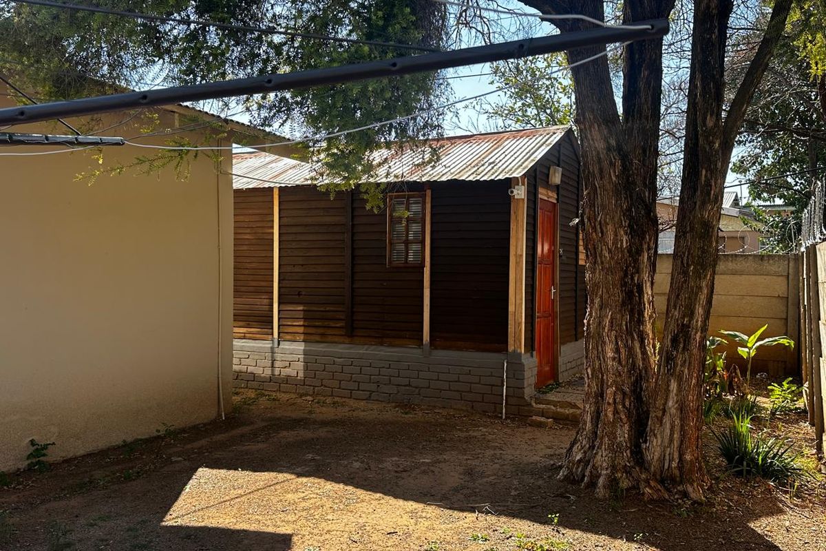 A detached timber-clad outbuilding with a corrugated metal roof, situated in a rear garden area.