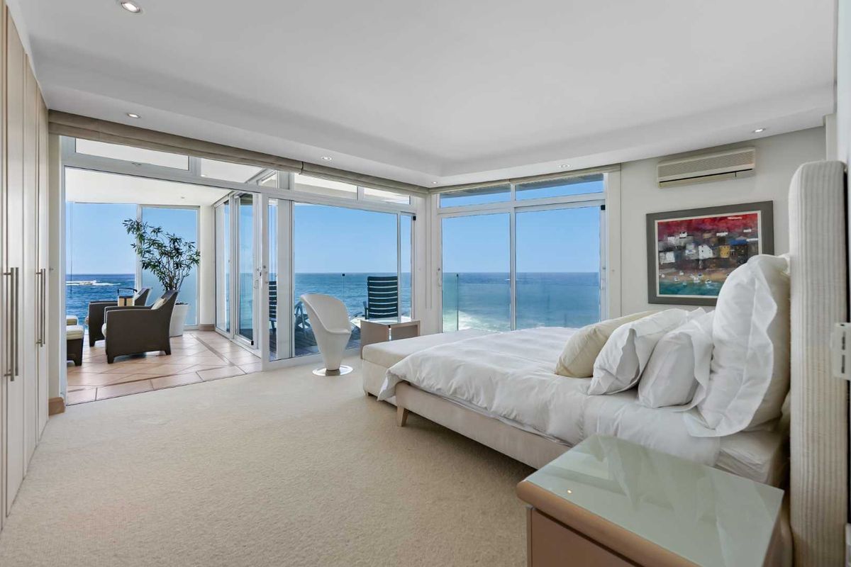 Spacious bedroom featuring built-in cupboards, air conditioning, and expansive sliding glass doors opening onto a balcony with panoramic ocean views.