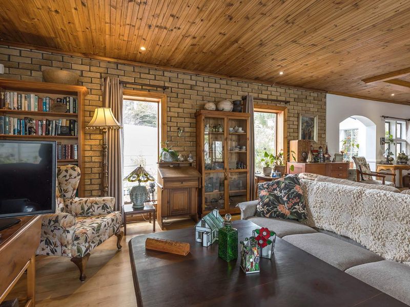 A cozy living room featuring exposed brick walls, a warm timber tongue and groove ceiling, and recessed lighting, creating a rustic and inviting atmosphere.