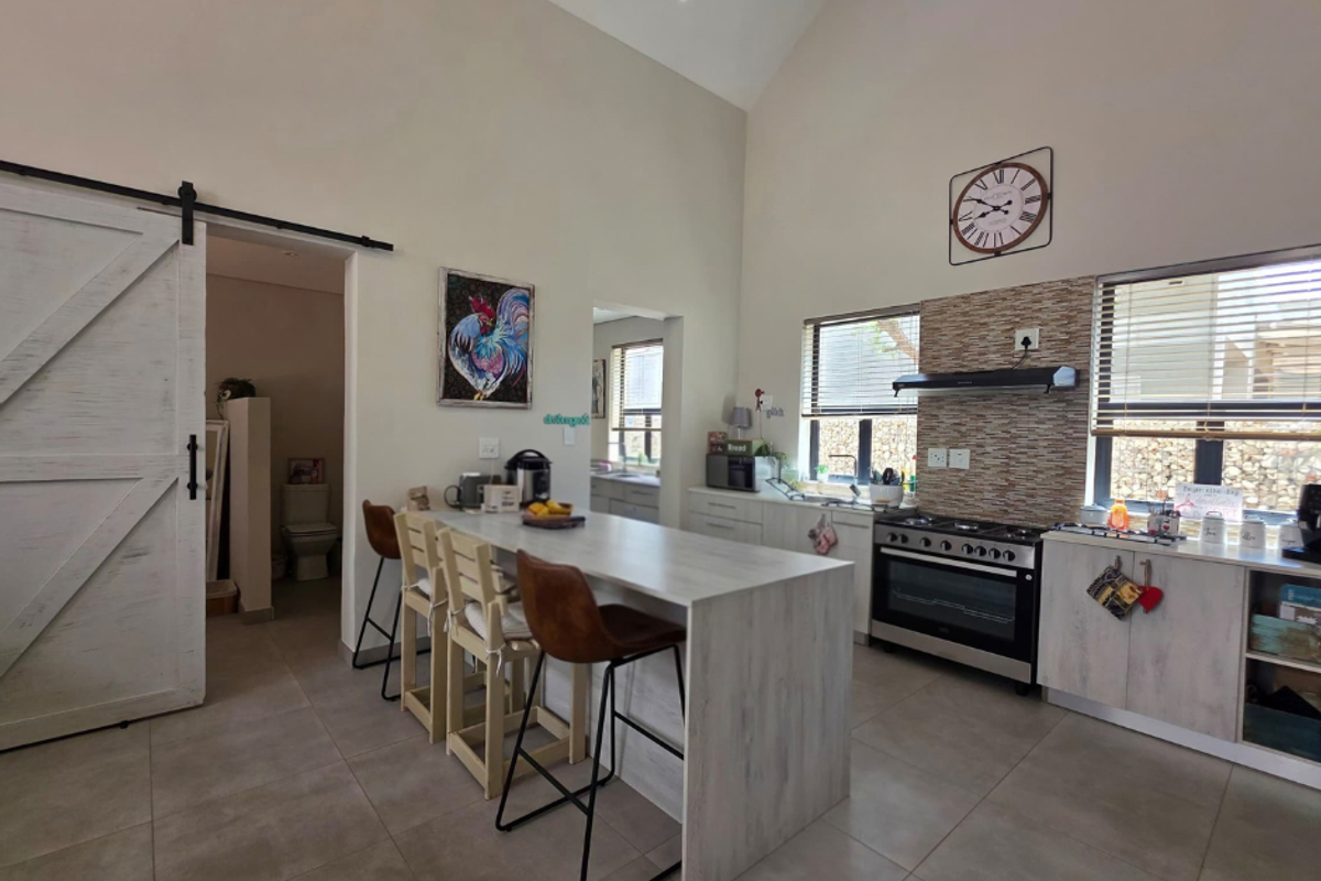 Modern kitchen featuring a central island, gas stove with extractor, tiled backsplash, and high vaulted ceilings, complemented by a sliding barn door.
