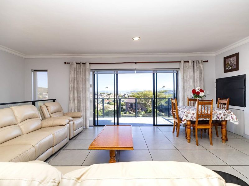 Spacious open-plan living and dining area featuring large sliding glass doors that open onto a balcony with scenic views.